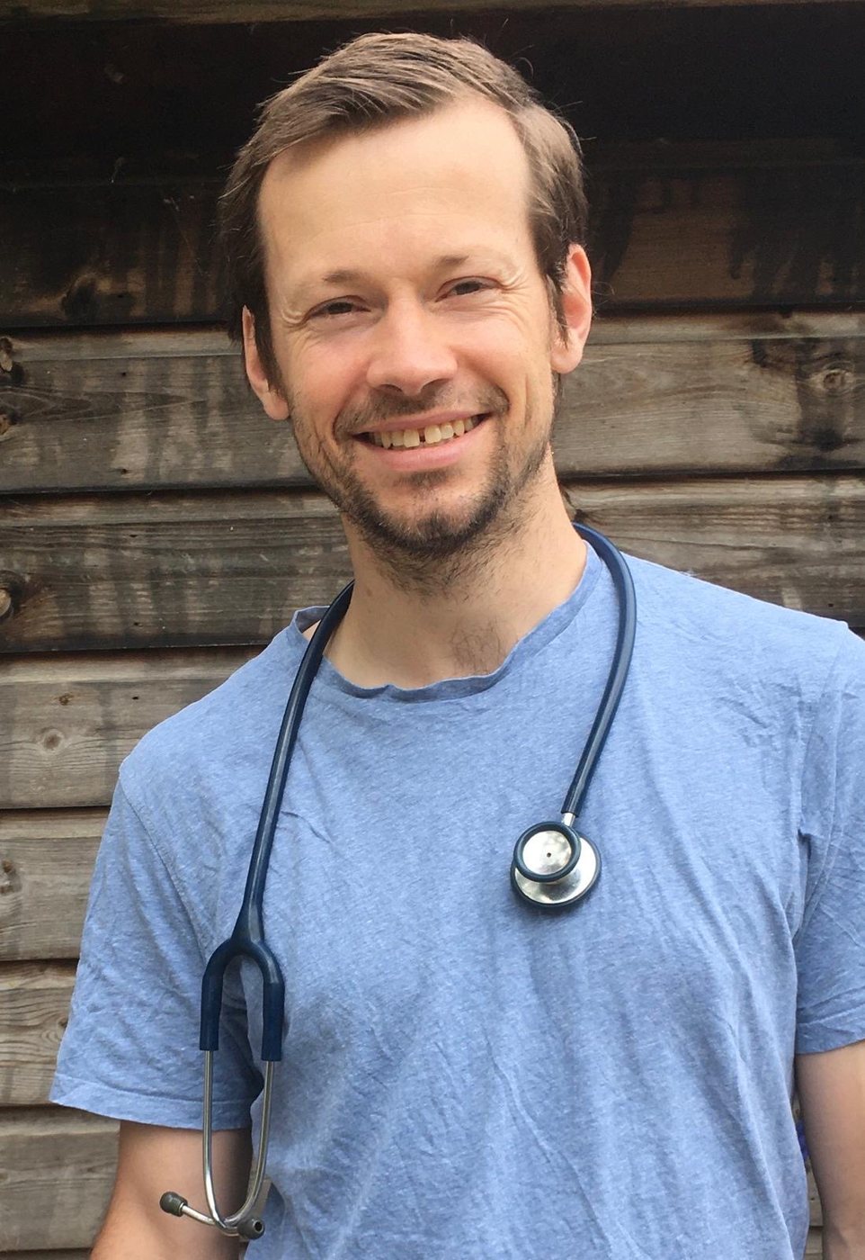 Tom, smiling, with a stethoscope round his neck