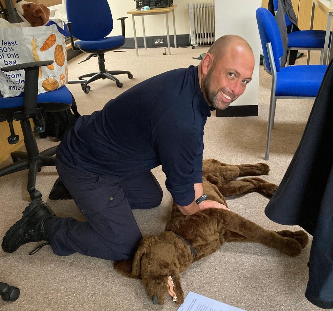 An instructor demonstrating canine first aid on a training mannequin